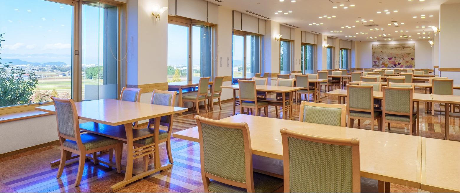 大きな窓から外の景色が見える、木目のテーブルと椅子が並んだ洋食会場「GRAND TABLE」