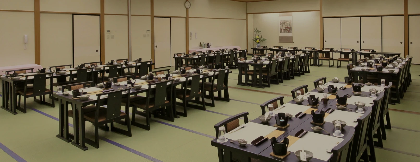畳の宴会場にテーブルと椅子がセッティングされた和風会場の内観。