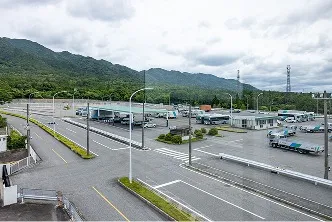 山々に囲まれた、大型トラックやバスが駐車された広大な貸出コース。