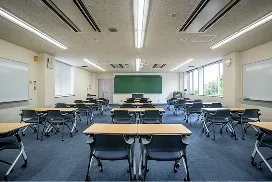 黒板と多数の学習用デスクが並ぶ研修室の様子。