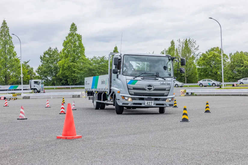 パイロンが設置された広場で車両操作を訓練するトラック
