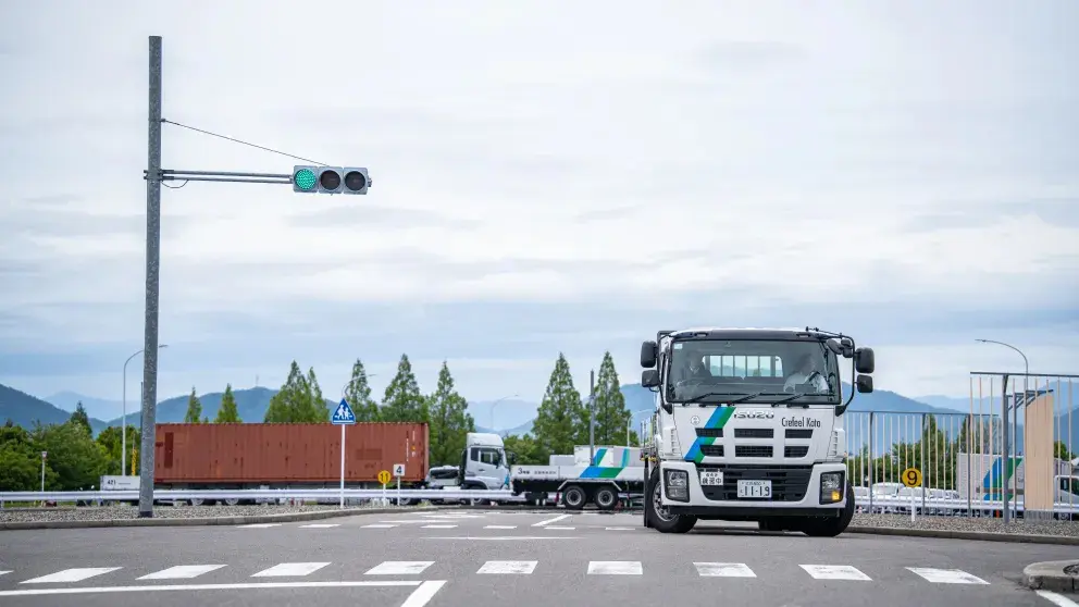 教習コースの信号交差点を走行する大型トラック。