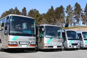 「Crefeel Koto」のロゴと緑のラインが入った、シルバーの送迎バスが大きさ順に4台並んでいる様子。