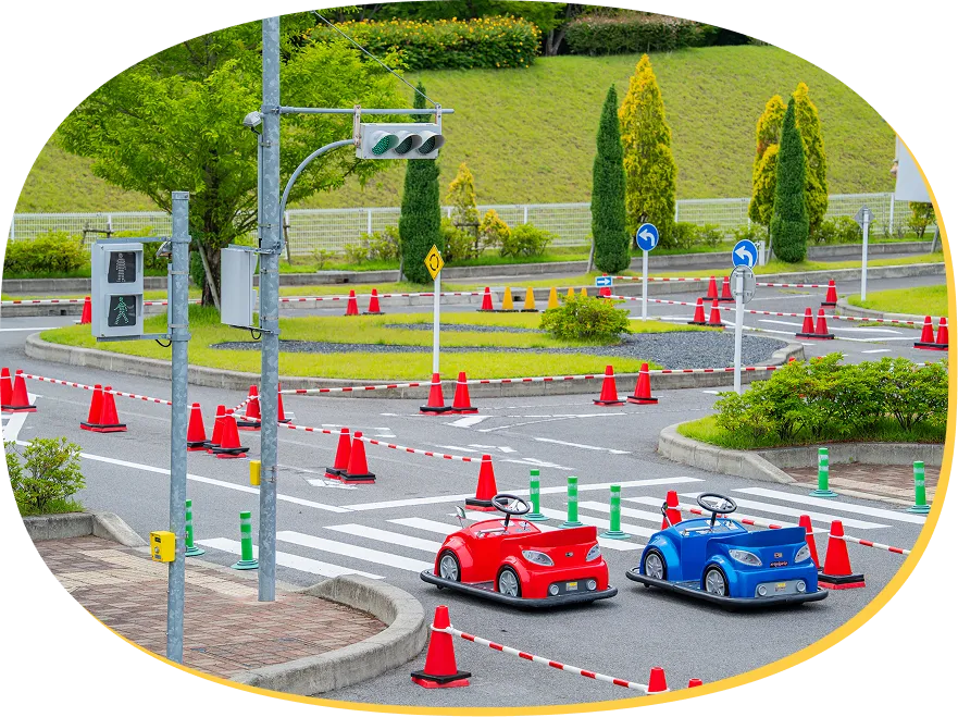 横断歩道や信号機のあるコースに置かれた、赤いEVカーと青いEVカー。