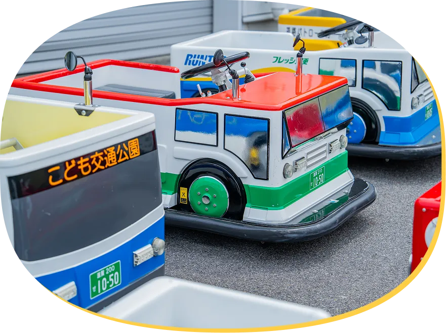 緑と赤のトラックや「こども交通公園」と書かれた青い車体など、色とりどりの働く車のEVカー。