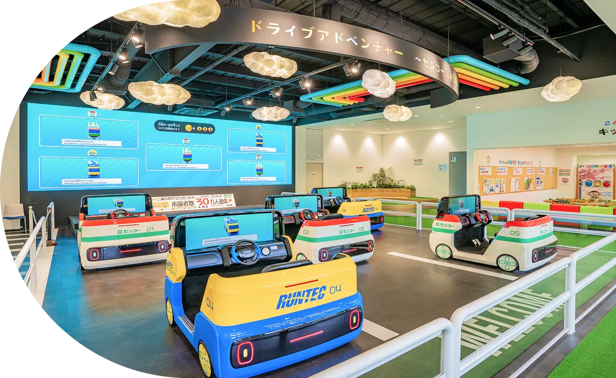 大型モニターと複数の子供向け運転シミュレーター機が並ぶ室内アトラクション「ドライブアドベンチャー」。
