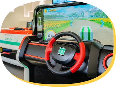 運転席目線で見る、シミュレーターのハンドルとゲーム画面。