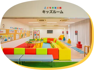 キッズルームの看板と、カラフルなソファや遊具が並ぶ室内の全景。