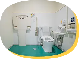 手すり付き便座とおむつ交換台が設置された多目的トイレの内部。