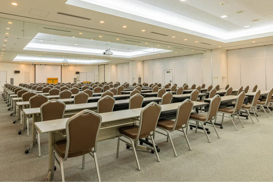 スクール形式の座席が整然と並んだ、明るい内装の広々とした研修・会議用ホール。