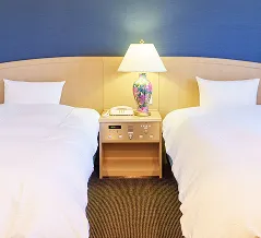 2台のベッドと中央にナイトランプが配置された、青い壁面が印象的な落ち着いた雰囲気のツインルーム。
