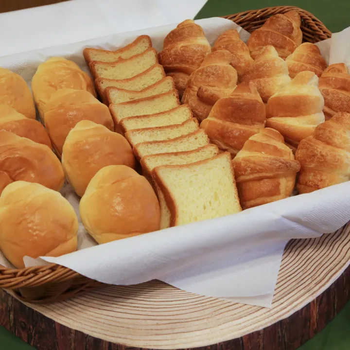 バスケットに美しく盛り付けられたクロワッサンやロールパンなどの焼きたてパン