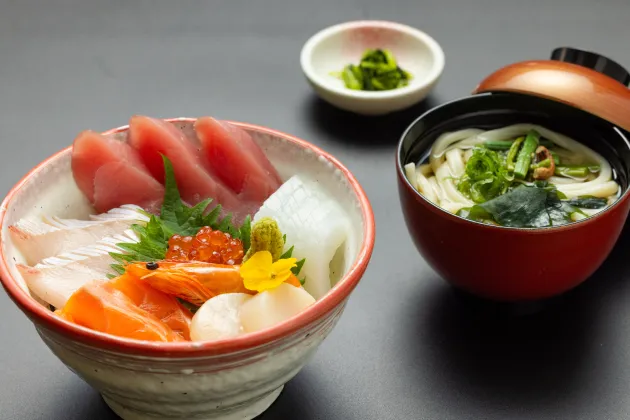 まぐろやサーモンなどが盛り付けられた海鮮丼と温かいうどんのセット