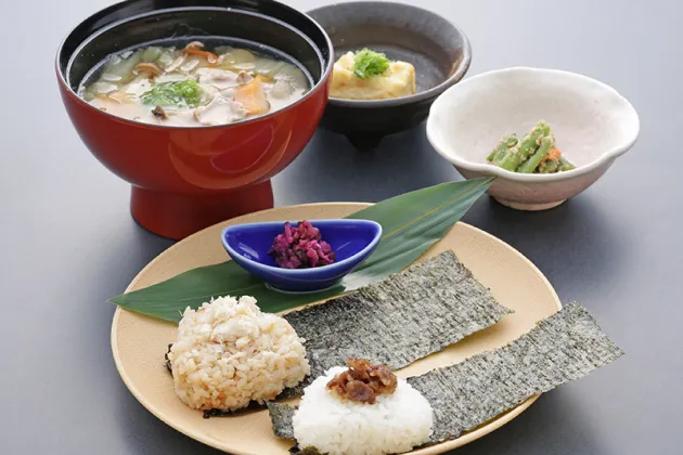 おにぎり、海苔、具だくさんの汁物、小鉢が並ぶ和食のセット