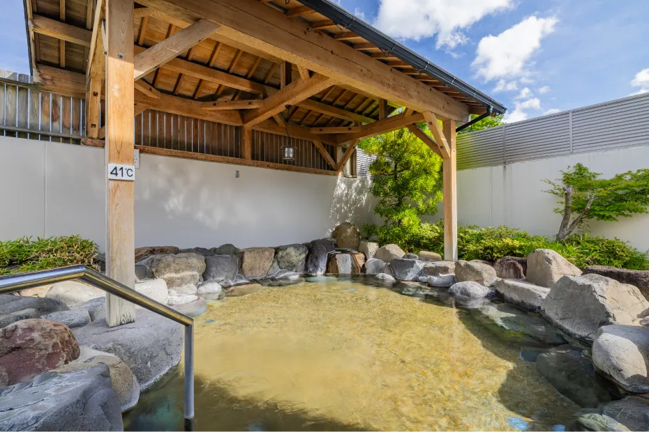 岩場に囲まれ、一部には木製の屋根が設置された広々とすごせる露天風呂。