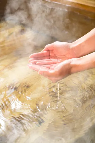 湯気が立ち上る心地よいお湯。そのお湯を両手ですくい上げている、リラックスしたひととき。